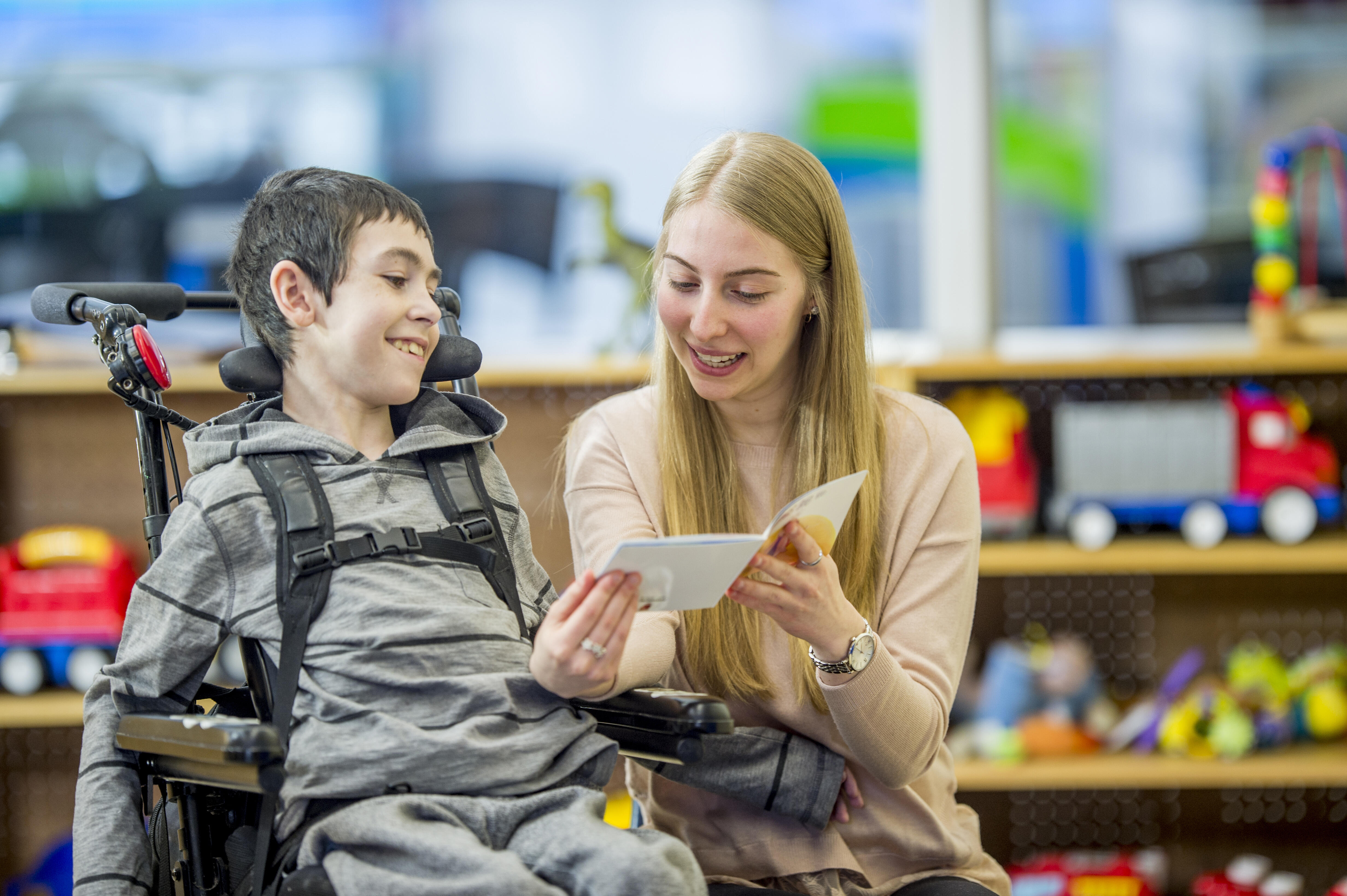 Teacher reading a book to a student in a wheelchair