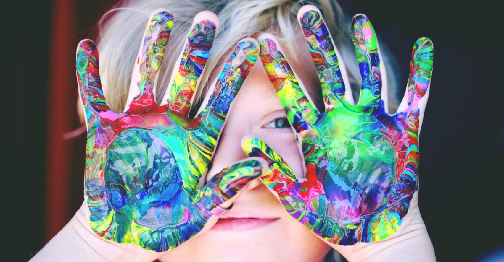Student showing hands colored in paint covering face