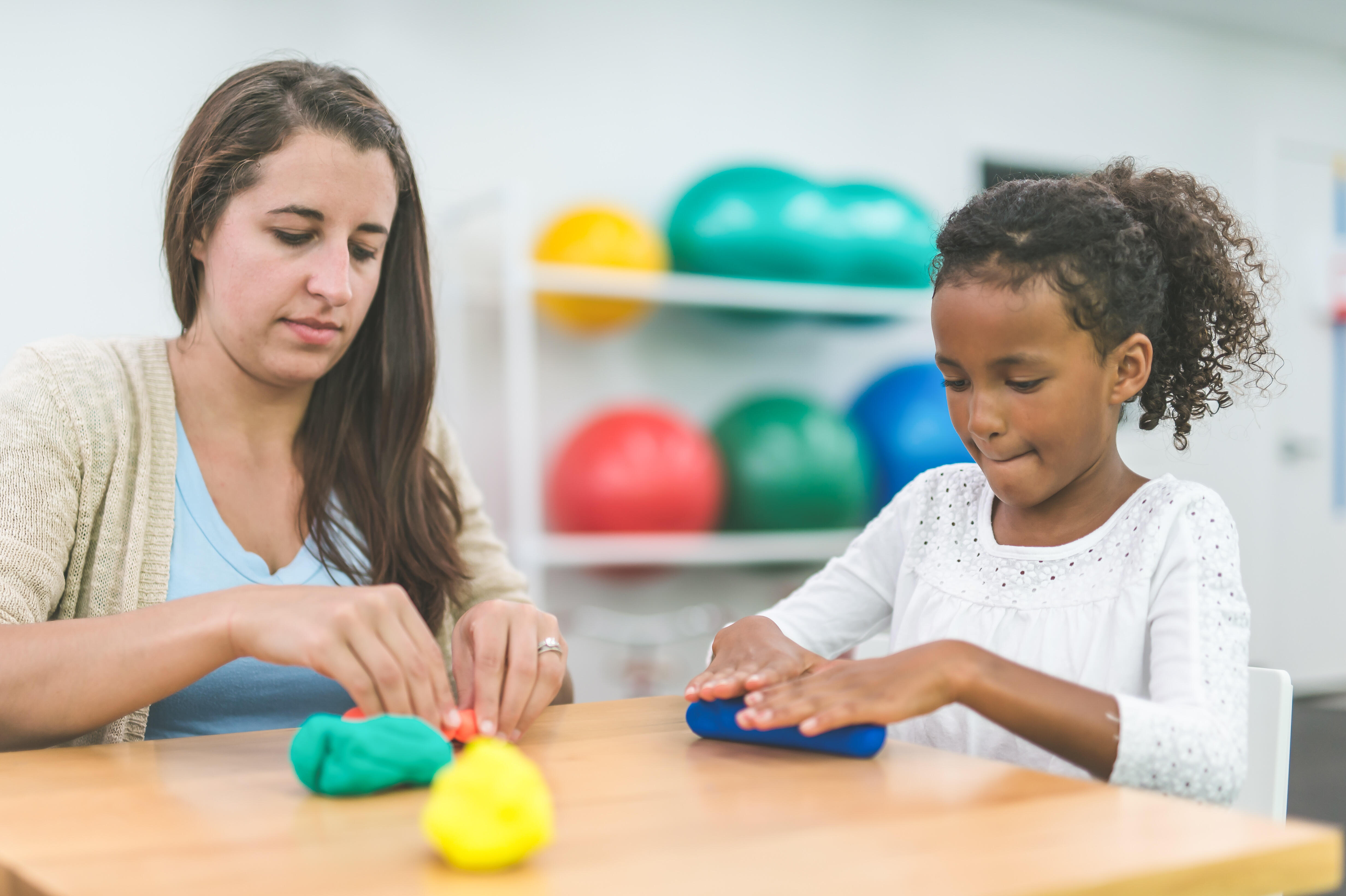 A female occupational therapist is doing rehabilitation with a child patient